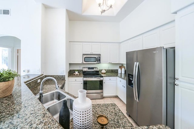 kitchen featuring sink, dark stone countertops, white cabinets, a high ceiling, and stainless steel appliances