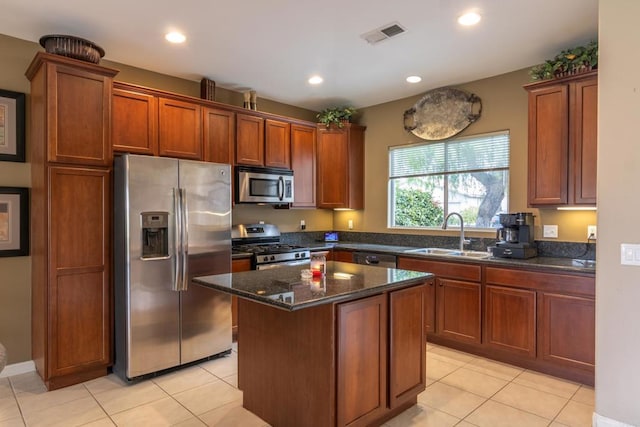 kitchen with sink, dark stone countertops, a kitchen island, stainless steel appliances, and light tile patterned flooring