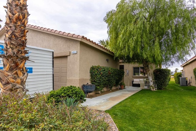 exterior space featuring a garage, central AC, and a lawn