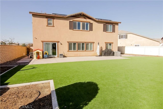 back of property with solar panels, a lawn, and a patio area