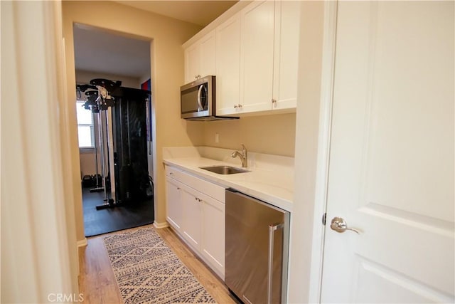 kitchen featuring white cabinetry, refrigerator, sink, and light wood-type flooring