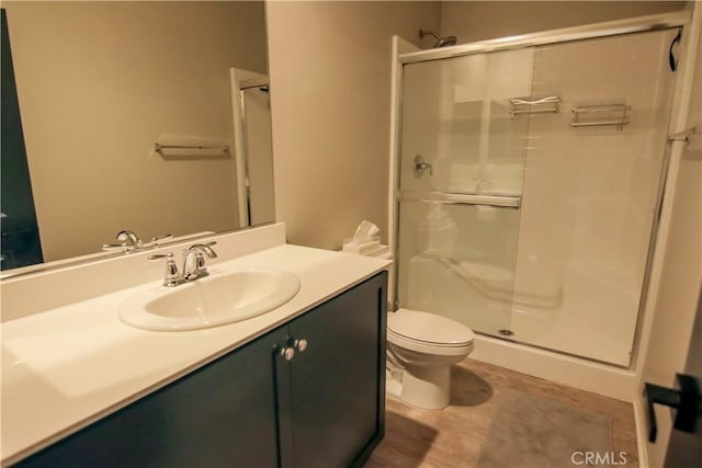 bathroom featuring hardwood / wood-style flooring, vanity, toilet, and a shower with door