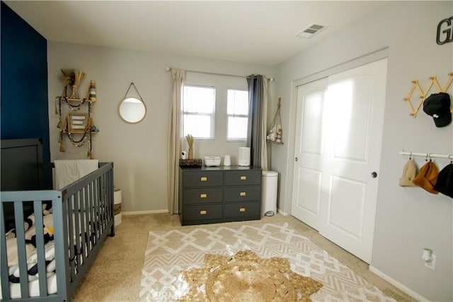 bedroom with a nursery area, light carpet, and a closet