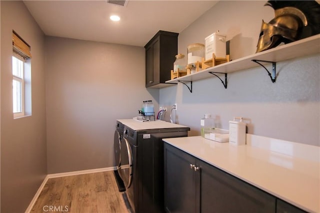 laundry area featuring cabinets, washing machine and clothes dryer, and light wood-type flooring