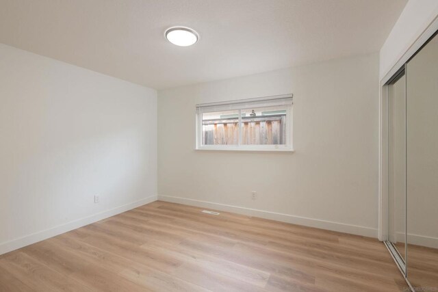 unfurnished bedroom with light hardwood / wood-style flooring and a closet