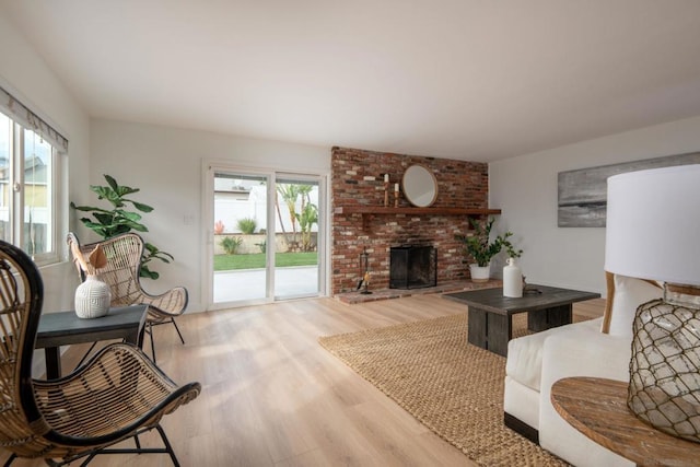 living room featuring a brick fireplace and light wood-type flooring