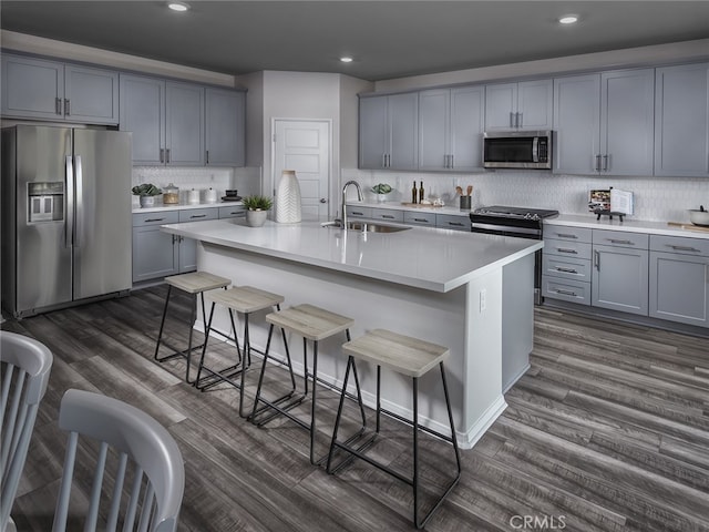 kitchen with a breakfast bar, stainless steel appliances, a kitchen island with sink, and sink