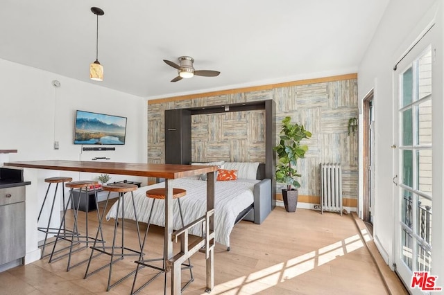 interior space with ceiling fan, radiator heating unit, and light wood-type flooring