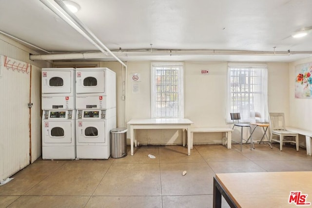 laundry area featuring tile patterned flooring, stacked washer and clothes dryer, and plenty of natural light