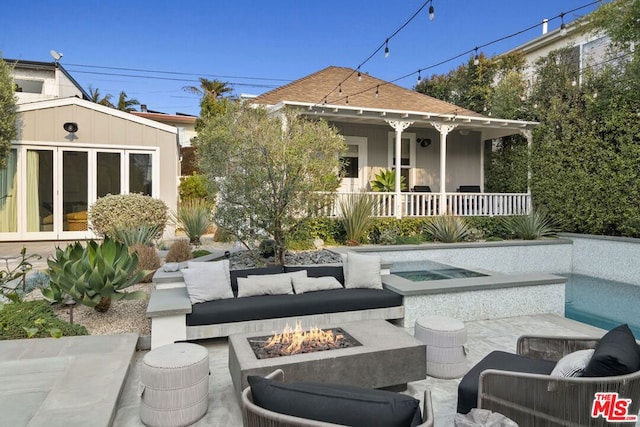 rear view of house with an outdoor structure, covered porch, a patio, and an outdoor living space with a fire pit