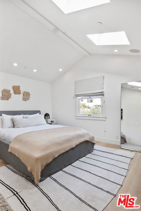 bedroom featuring vaulted ceiling with skylight and light wood-type flooring