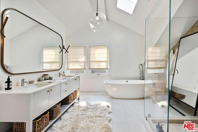 bathroom with tile patterned floors, vanity, vaulted ceiling with skylight, and a bathtub