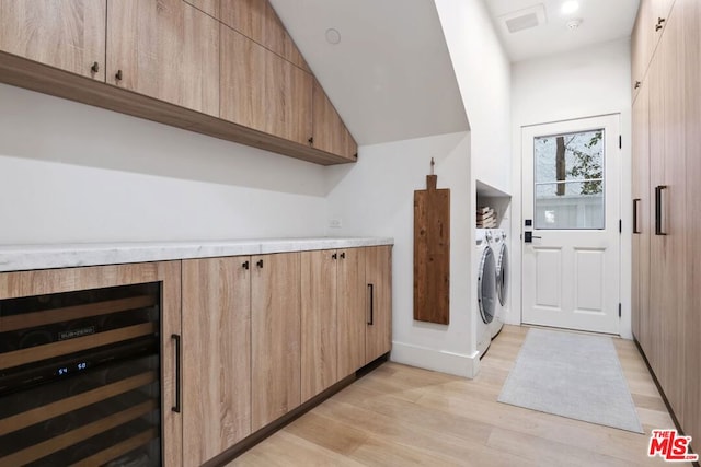 washroom with wine cooler, light hardwood / wood-style flooring, and separate washer and dryer