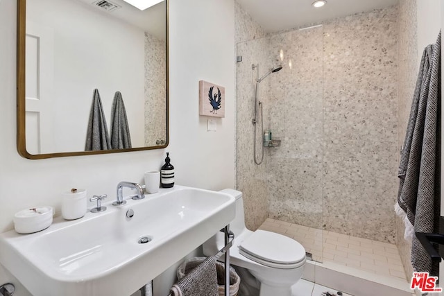 bathroom with sink, tile patterned floors, toilet, and tiled shower