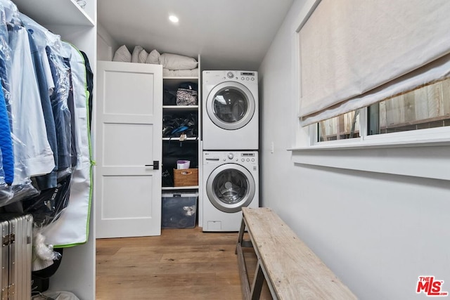 laundry room featuring stacked washer / drying machine and hardwood / wood-style floors