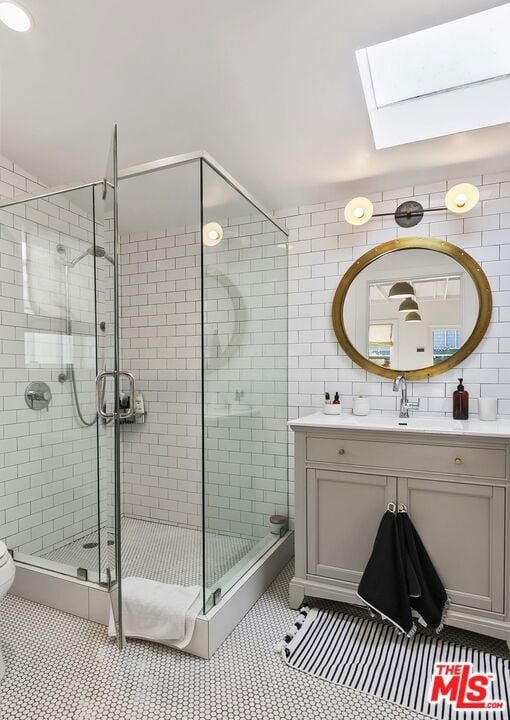 bathroom featuring a skylight, vanity, an enclosed shower, and toilet