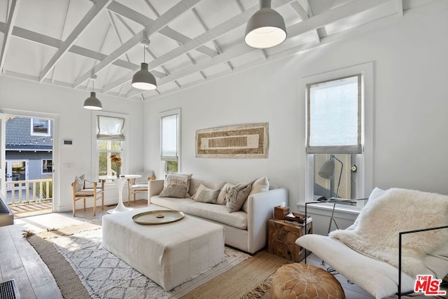 living room with plenty of natural light, light hardwood / wood-style flooring, and vaulted ceiling with beams