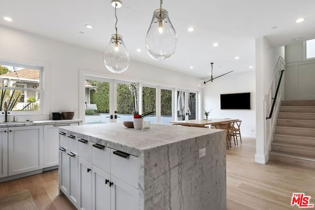 kitchen with light stone counters, decorative light fixtures, french doors, and a kitchen island