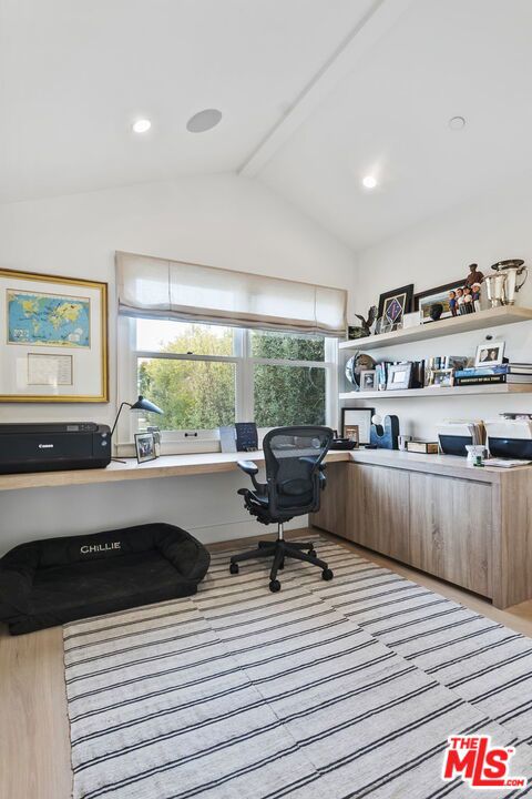 office area featuring lofted ceiling, built in desk, and light hardwood / wood-style flooring