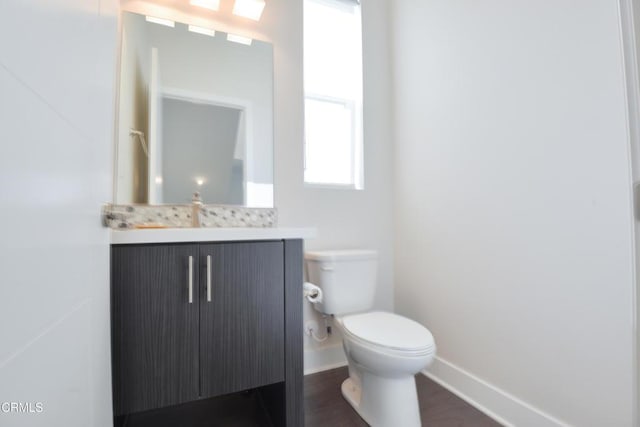 bathroom with vanity, toilet, and hardwood / wood-style floors