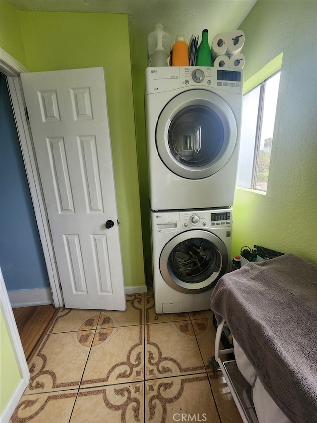 laundry area featuring stacked washer / drying machine and light tile patterned floors