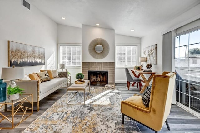 living room with vaulted ceiling, plenty of natural light, dark hardwood / wood-style floors, and a brick fireplace