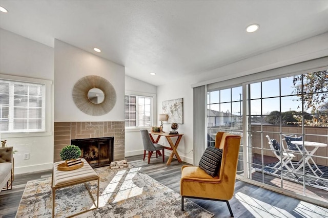 sitting room featuring hardwood / wood-style flooring, a brick fireplace, and lofted ceiling