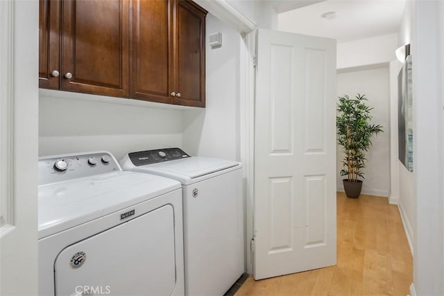 washroom with separate washer and dryer, light hardwood / wood-style flooring, and cabinets