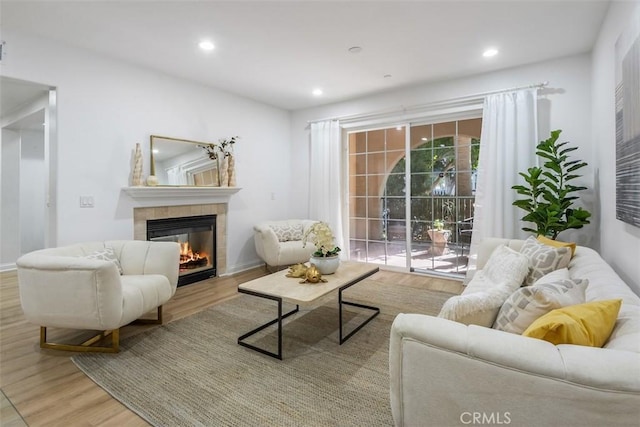 living room featuring a tile fireplace, plenty of natural light, and light hardwood / wood-style floors