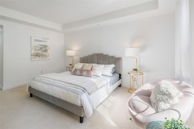 bedroom with a tray ceiling and light carpet