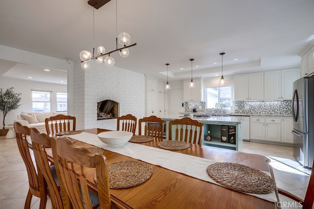 dining space featuring sink, light tile patterned floors, a fireplace, and a healthy amount of sunlight