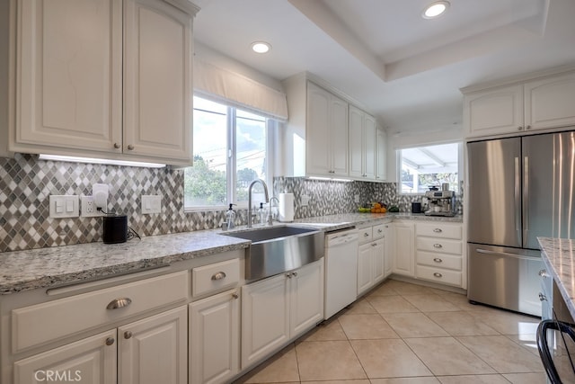 kitchen featuring white dishwasher, light tile patterned floors, white cabinetry, and stainless steel fridge