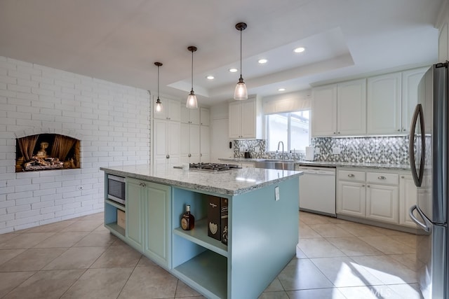 kitchen with stainless steel appliances, a kitchen island, white cabinets, and a tray ceiling