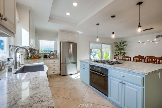 kitchen featuring sink, white cabinetry, appliances with stainless steel finishes, a tray ceiling, and a kitchen island