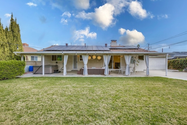 rear view of house featuring a hot tub, an outdoor hangout area, a lawn, and solar panels