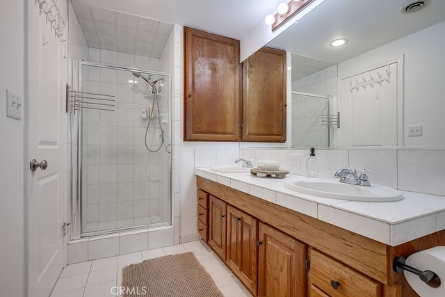 bathroom with tile patterned flooring, vanity, backsplash, and an enclosed shower