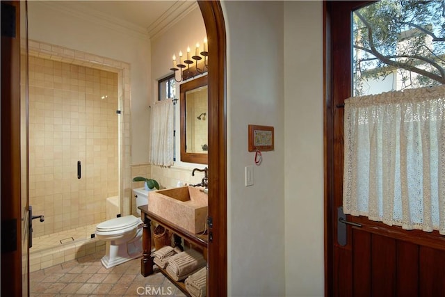 bathroom with a tile shower, sink, ornamental molding, and toilet