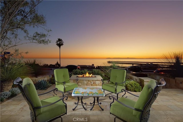 patio terrace at dusk with a water view and a fire pit