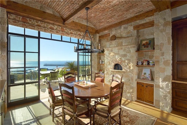 dining area featuring hardwood / wood-style flooring, brick ceiling, a water view, a notable chandelier, and lofted ceiling with beams