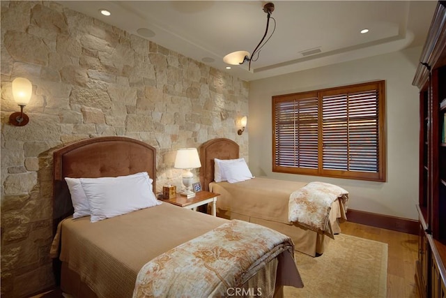 bedroom featuring light hardwood / wood-style floors and a raised ceiling