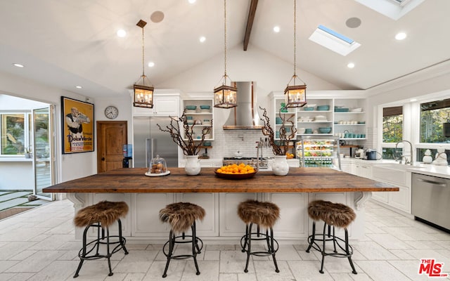 kitchen featuring stainless steel appliances, a kitchen island, butcher block counters, and a breakfast bar area