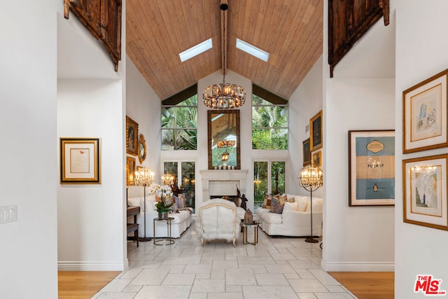 living area with an inviting chandelier, wood ceiling, a skylight, and high vaulted ceiling