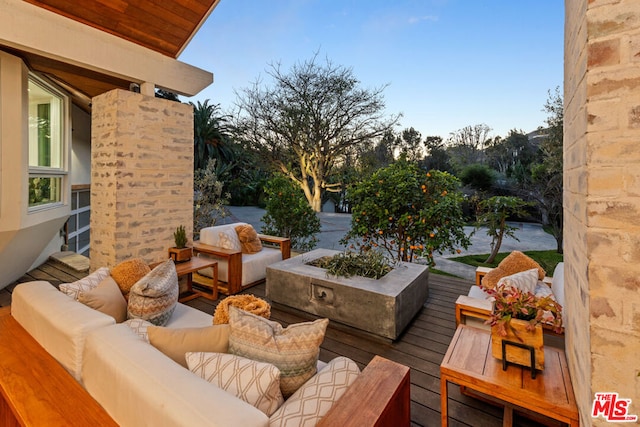 wooden terrace with an outdoor living space with a fire pit