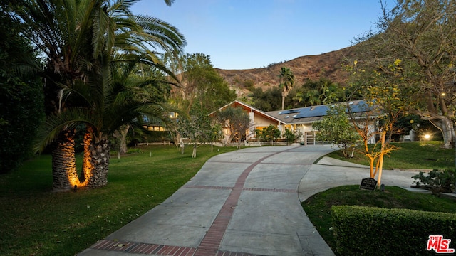 exterior space featuring a mountain view, a front lawn, and solar panels