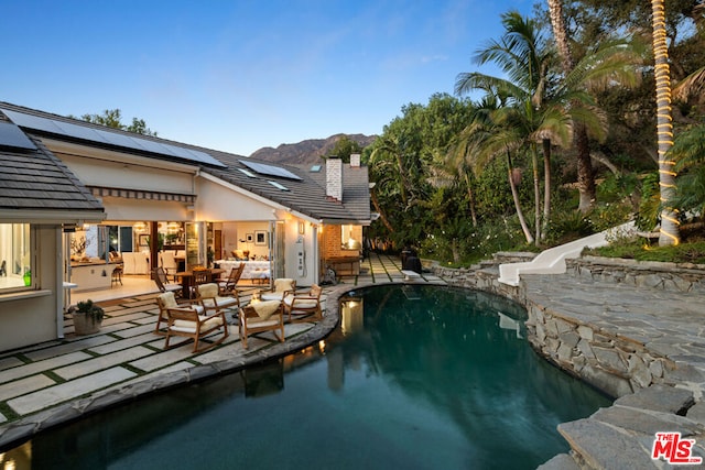 view of pool featuring an outdoor living space, a mountain view, and a patio area