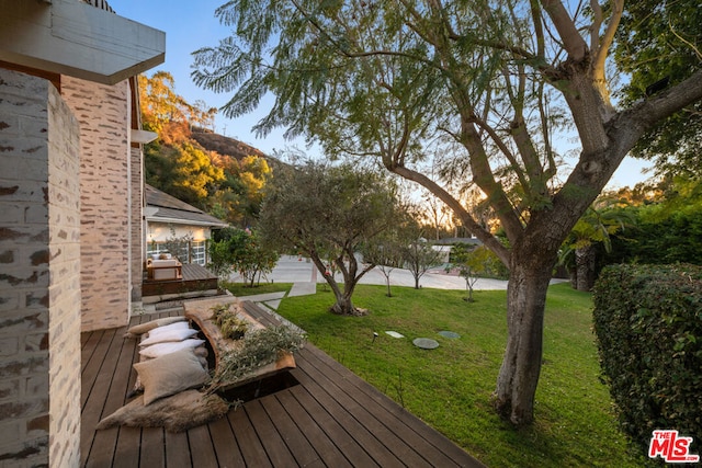 deck at dusk featuring a lawn