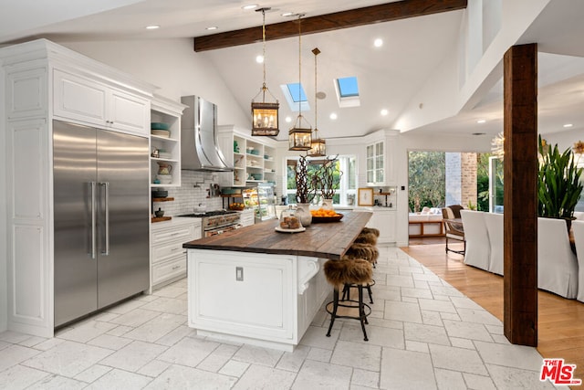 kitchen featuring white cabinetry, premium appliances, wall chimney range hood, and a kitchen island