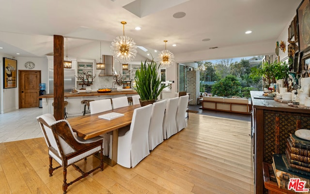 dining area featuring vaulted ceiling, a chandelier, and light wood-type flooring