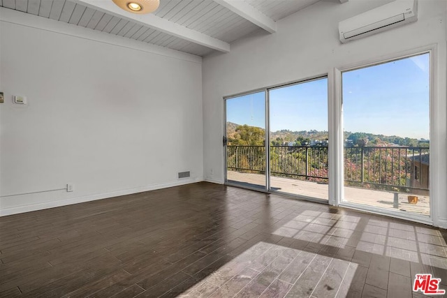 unfurnished room with beamed ceiling, a wealth of natural light, dark hardwood / wood-style floors, and a wall mounted AC