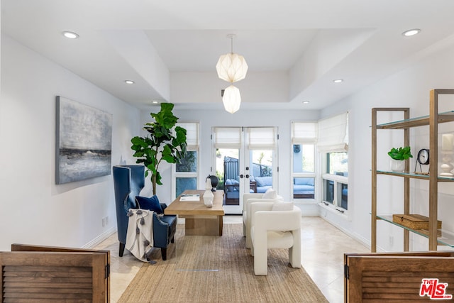 tiled living room featuring french doors and a tray ceiling